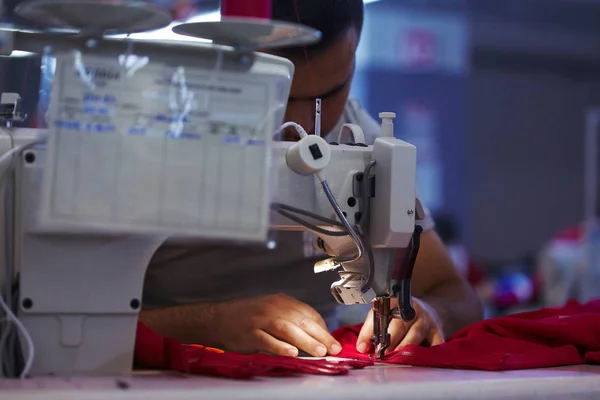 Pracovníka nebo továrně šicí červený hadr na šicí stroj — Stock fotografie