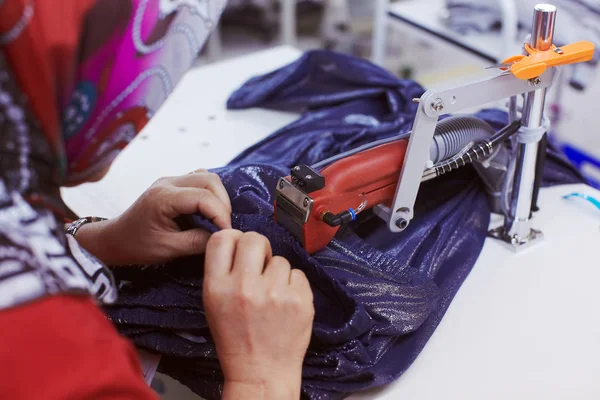 Finishing work on cloth factory - extra threads cutting machine trimmer in hand of worker