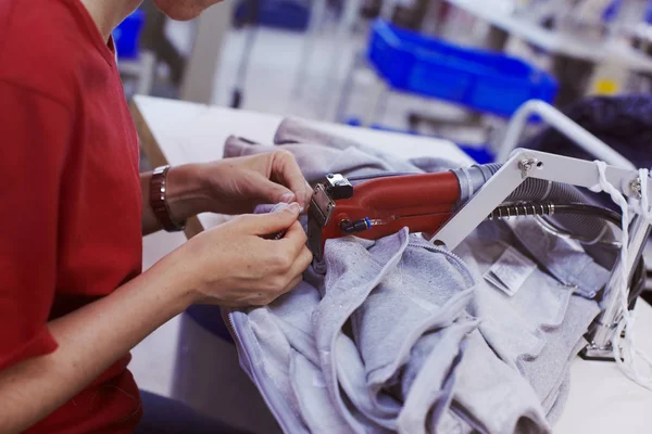 Dokončovací práce na továrnu na sukno - další vlákna řezání zastřihovač stroj v ruce pracovníka — Stock fotografie