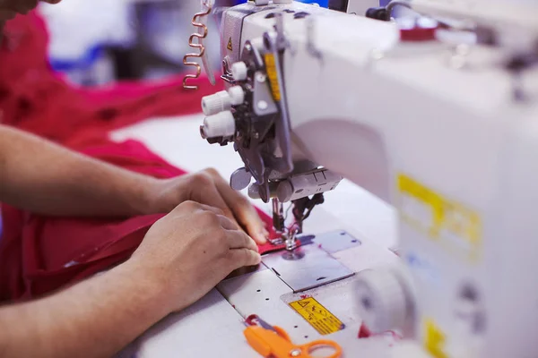 Textile factory workers hands sewing cloth on professional sewing machine