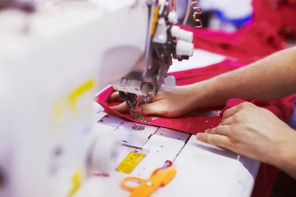 Textile factory workers hands sewing cloth on professional sewing machine