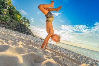 Yakışıklı sekiz yıl çocuk sahilde gerçekleştirir akrobatik çizimler bir