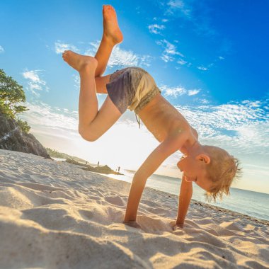 Yakışıklı sekiz yıl çocuk sahilde gerçekleştirir akrobatik çizimler bir