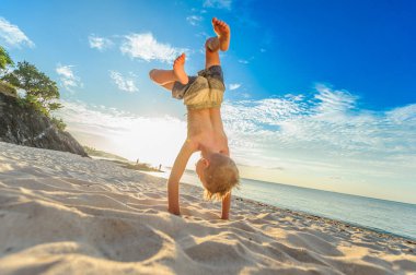Yakışıklı sekiz yıl çocuk sahilde gerçekleştirir akrobatik çizimler bir