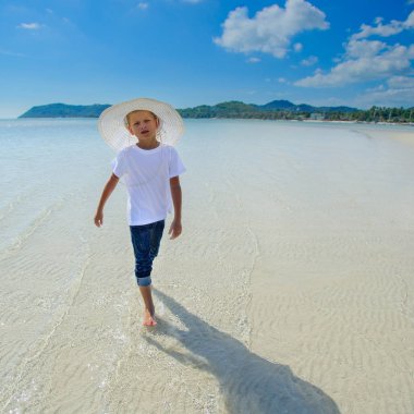 Çok güzel çocuk tropik sahilde eğleniyor. Beyaz t-shirt, da