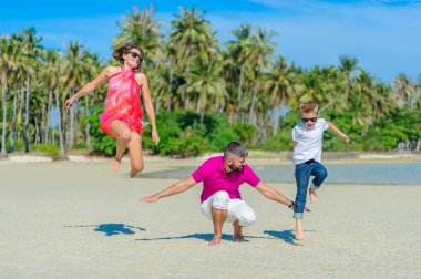 Aile üç çalışan ve tropik sahil boyunca la atlama