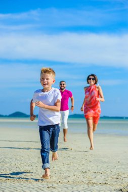 Çocuk ve ailesi çalıştıran ve tropik sahil boyunca atlama