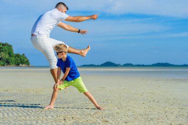 Mutlu baba ve oğul tropikal plaj, gülen ve enjoing