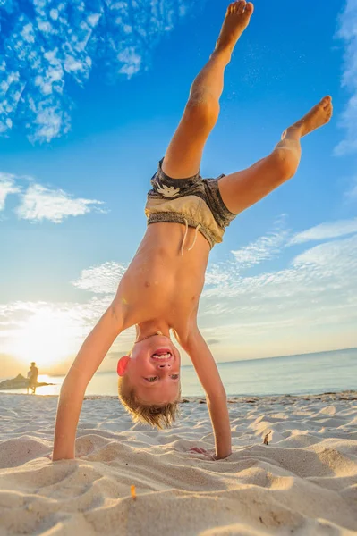 Guapo ocho años chico en playa realiza acrobacias bocetos un —  Fotos de Stock