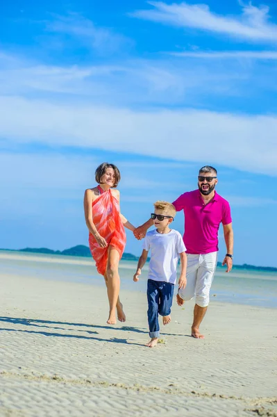 Familia de tres corriendo y saltando por la playa tropical, la —  Fotos de Stock