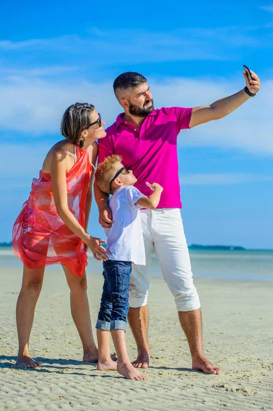 Familia feliz de tres en la playa tropical, riendo y ordenando — Foto de Stock