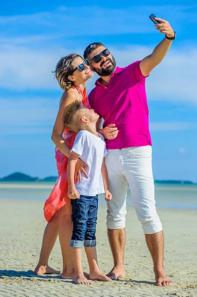 Üç tropikal, mutlu aile plaj, gülüyor ve emretmek