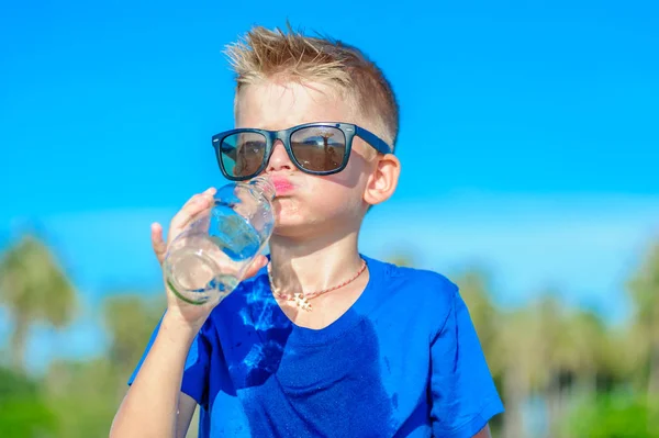 Retrato de un chico guapo sediento en gafas de sol bebiendo agua —  Fotos de Stock