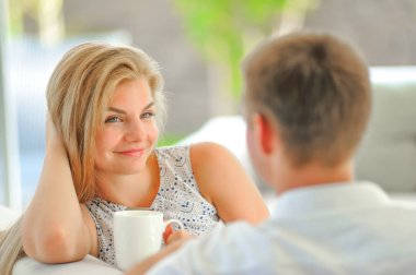 Yakışıklı uzun saçlı genç sarışın kadın kanepe propp üzerinde oturuyordu