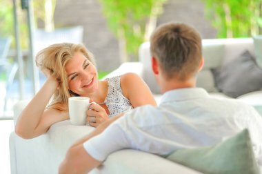 Yakışıklı uzun saçlı genç sarışın kadın kanepe propp üzerinde oturuyordu