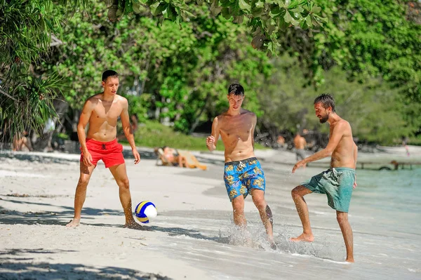 Amigos jugando al fútbol en la soleada playa tropical — Foto de Stock