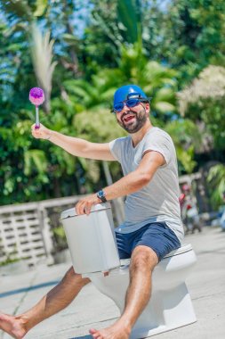 Gözlük installe olan tuvalet, ata biner gibi sakallı adam