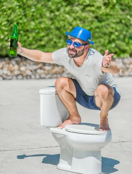 Vousatý muž v brýle rozkročmo na WC, které je instalované — Stock fotografie