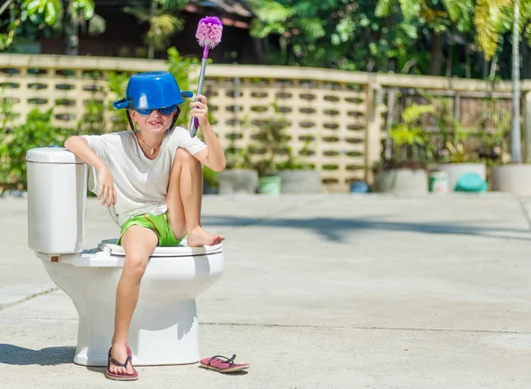 Absurdes Bild: Netter Junge mit Brille sitzt auf der Toilette, die — Stockfoto