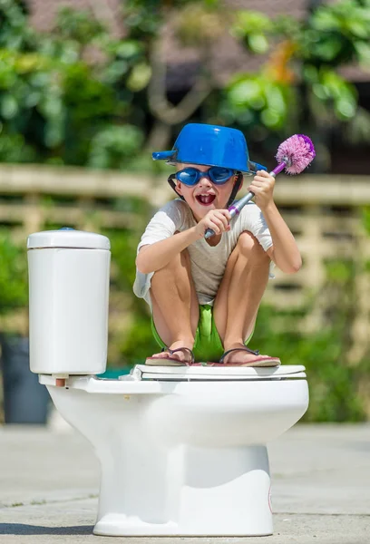 Absurdo imagem: menino bonito em óculos sentados no banheiro, que — Fotografia de Stock