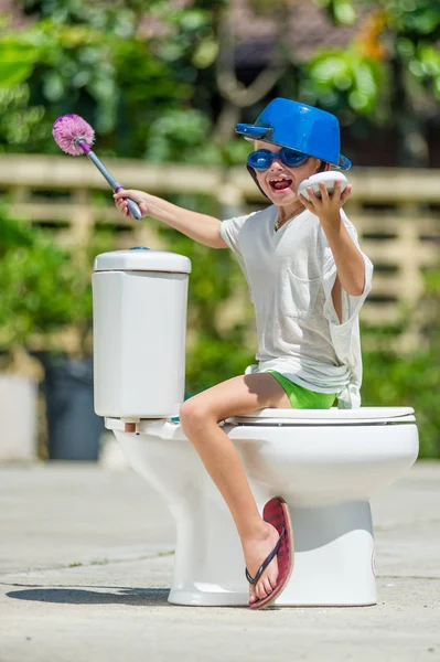 Абсурдне зображення в туалеті: милий хлопчик в окулярах сидить — стокове фото