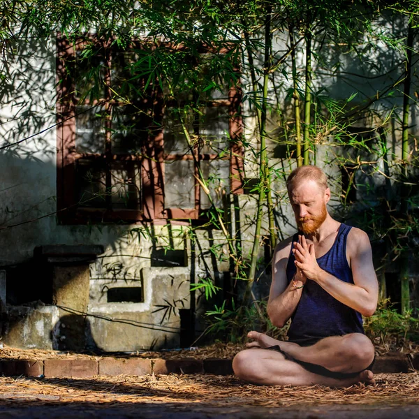 Yoga teacher portrait. Red hair man with a red beard showing the