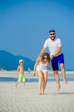 Üç çöl güneşli kumsalda eğleniyor mutlu genç aile