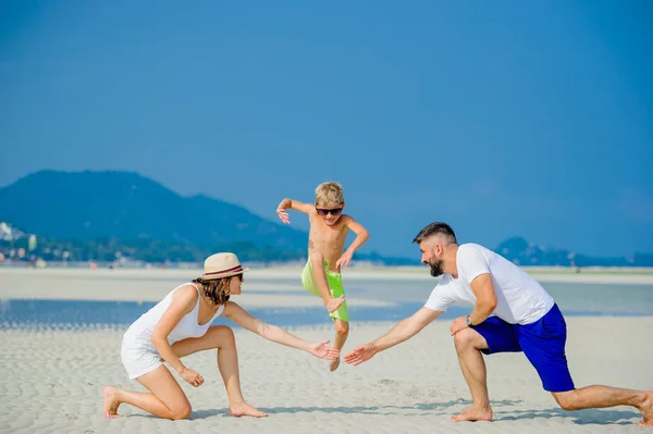 Feliz familia joven de tres divirtiéndose en la playa soleada desierto — Foto de Stock