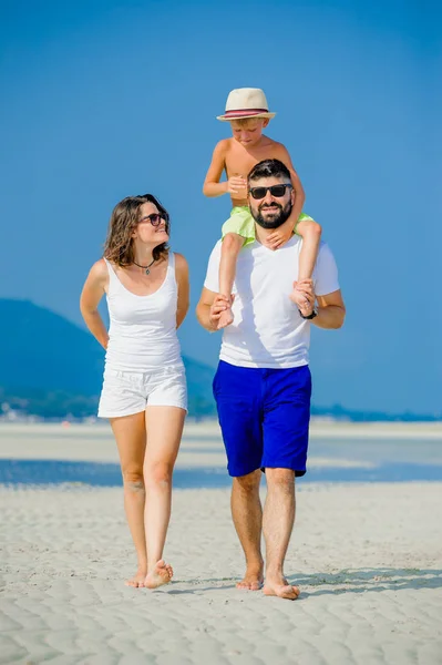 Feliz familia joven de tres divirtiéndose en la playa soleada desierto — Foto de Stock