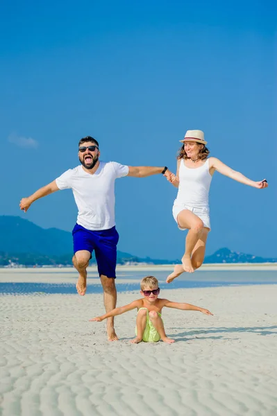 Feliz familia joven de tres divirtiéndose en la playa soleada desierto — Foto de Stock