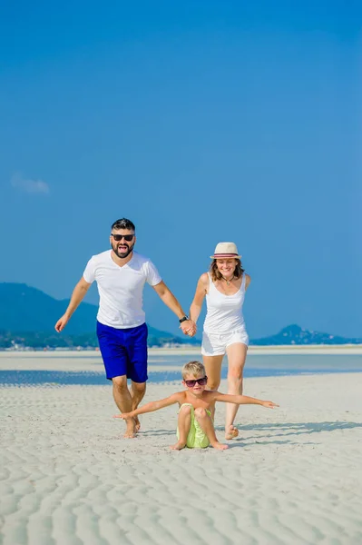 Happy young family of three having fun on the desert sunny beach Stock Picture
