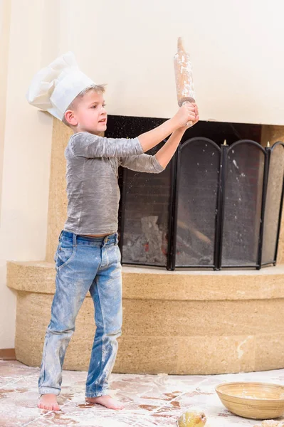 Un niño con sombreros de chef cerca de la chimenea de pie en la cocina — Foto de Stock