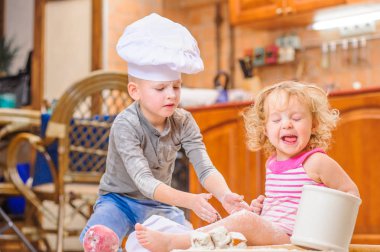 İki kardeş - erkek ve kız - kitc üzerinde oturan şefin şapka içinde