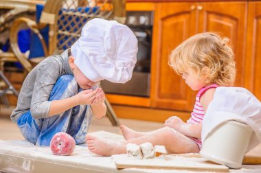 İki kardeş - erkek ve kız - kitc üzerinde oturan şefin şapka içinde