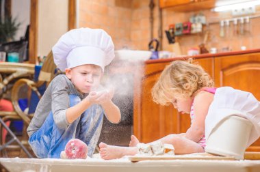 İki kardeş - erkek ve kız - kitc üzerinde oturan şefin şapka içinde