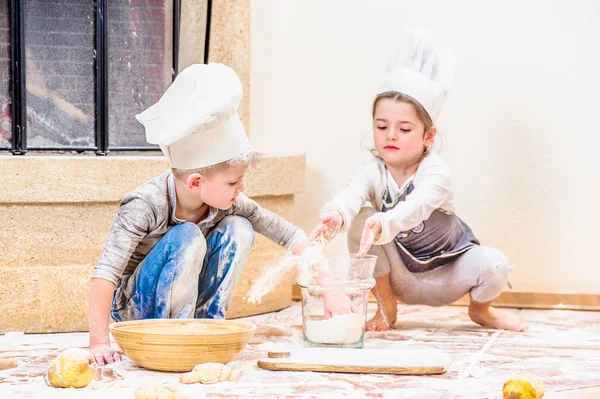 Dos hermanos - niño y niña - en sombreros de chef cerca de la chimenea — Foto de Stock