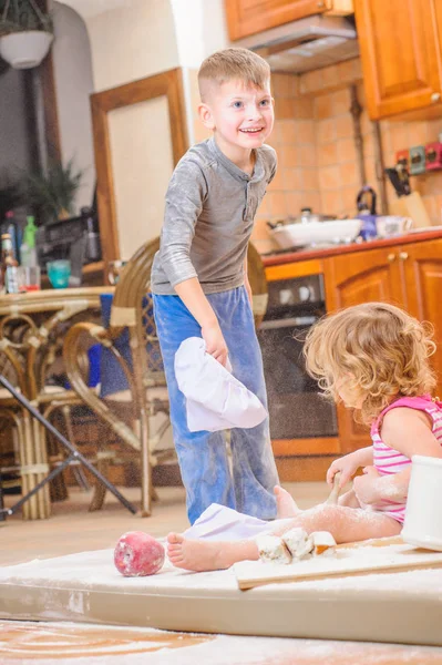 İki kardeş - erkek ve kız - kitc üzerinde oturan şefin şapka içinde