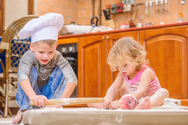 Dos hermanos - niño y niña - en sombreros de chef sentados en el kitc —  Fotos de Stock