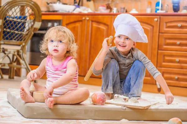 Dos hermanos - niño y niña - en sombreros de chef sentados en el kitc —  Fotos de Stock