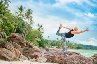 Güzel olgun yaşlı kadın bir ıssız tropikal beac Yoga yapıyor