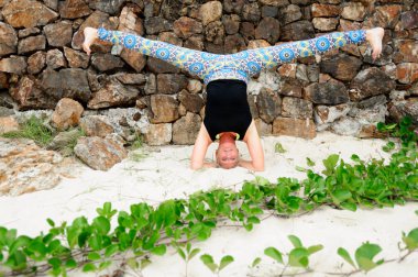 Güzel olgun yaşlı kadın bir ıssız tropikal beac Yoga yapıyor
