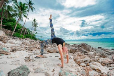 Güzel olgun yaşlı kadın bir ıssız tropikal beac Yoga yapıyor