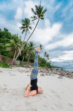 Güzel olgun yaşlı kadın bir ıssız tropikal beac Yoga yapıyor