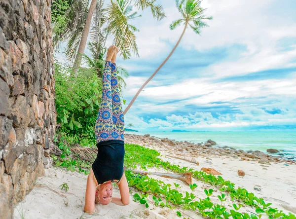 Güzel olgun yaşlı kadın bir ıssız tropikal beac Yoga yapıyor