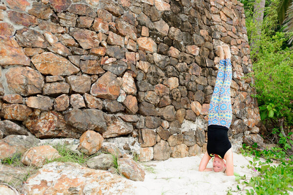 Beautiful mature aged woman doing yoga on a desert tropical beac