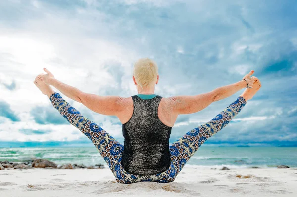 Bella donna anziana matura che fa yoga su un deserto tropicale beac — Foto Stock