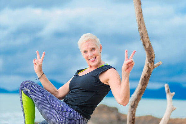 Beautiful mature aged woman doing yoga on a desert tropical beac