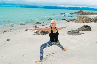 Güzel olgun yaşlı kadın bir ıssız tropikal beac Yoga yapıyor