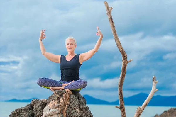 Beautiful mature aged woman doing yoga on a desert tropical beac — Stock Photo, Image