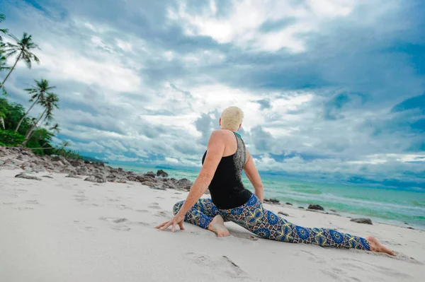 Mooie rijpe leeftijd vrouw doet yoga op een woestijn tropisch beac — Stockfoto